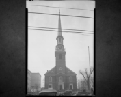 Black-and-white 1936 east view of First Presbyterian Church in Elizabeth with its tall clock tower and cars parked along Broad Street.