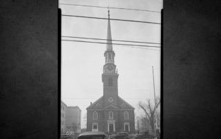 Black-and-white 1936 east view of First Presbyterian Church in Elizabeth with its tall clock tower and cars parked along Broad Street.