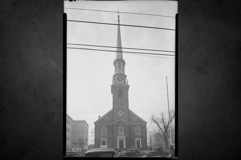 Black-and-white 1936 east view of First Presbyterian Church in Elizabeth with its tall clock tower and cars parked along Broad Street.
